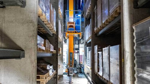 一台货物存取机正在堆放托盘的立体仓库货架间运行。