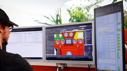 一名员工坐在计算机显示器前，其中一个显示器显示着3D设计图