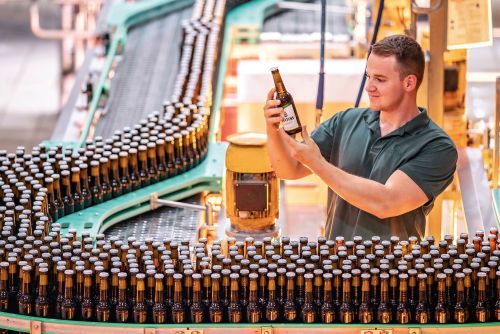 A man checks a beer bottle on the conveyor belt