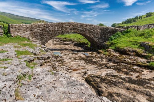 Old stone bridge over the dried-up river Skirfare in North Yorkshire, UK.
